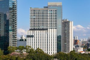 imagem mostra prédio do Hotel JW Marriott com outros prédios ao redor e céu azul ao fundo
