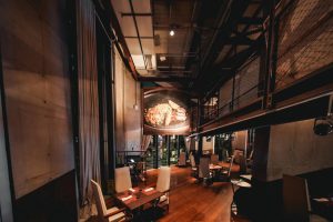 imagem mostra um bar com mesas, cadeiras e decoração de madeira