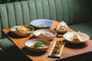 foto mostra mesa com 7 pratos de comidas diversas