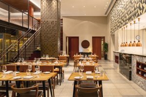 imagem mostra salão de um restaurantes com mesas e uma escada a esquerda