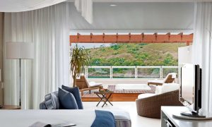 imagem mostra quarto de hotel com varanda de frente para o mar