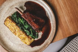 imagem mostra prato com costela bovina, mandioquinha gratinada e mostarda refogada