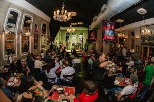 imagem mostra pessoas sentadas em mesas de um bar