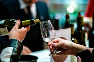 imagem mostra uma pessoa servindo vinho em uma taça