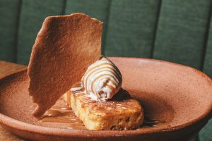 imagem mostra prato marrom com sobremesa sobre uma mesa