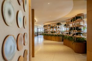 Entrada do restaurante Quint.e / The Westin São Paulo, com decoração contemporânea, estantes de madeira e ambientes integrados com plantas naturais