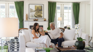 Casal desfruta de momento de descanso e conexão em uma elegante suíte do Palácio Tangará, cercada por decoração sofisticada, iluminação natural e vista para áreas verdes.